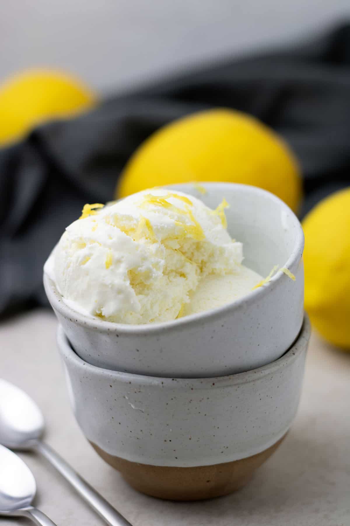 Lemon ice cream in a bowl, with some lemon laying next to it