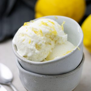 Lemon ice cream in a bowl, with some lemon laying next to it