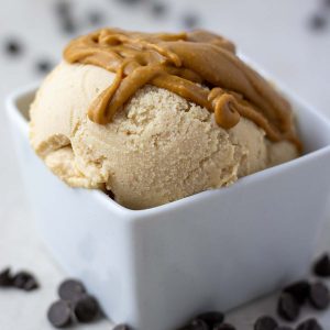peanut butter ice cream in a white bowl with chocolate chips laying around